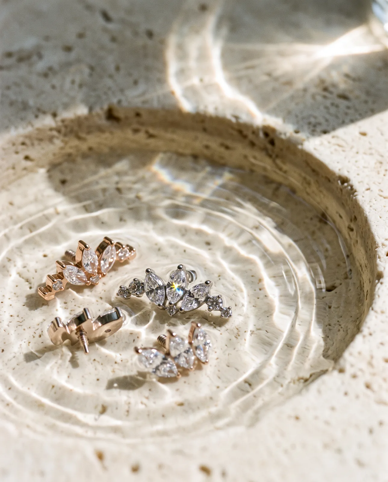 Piercing earrings resting in a stone basin