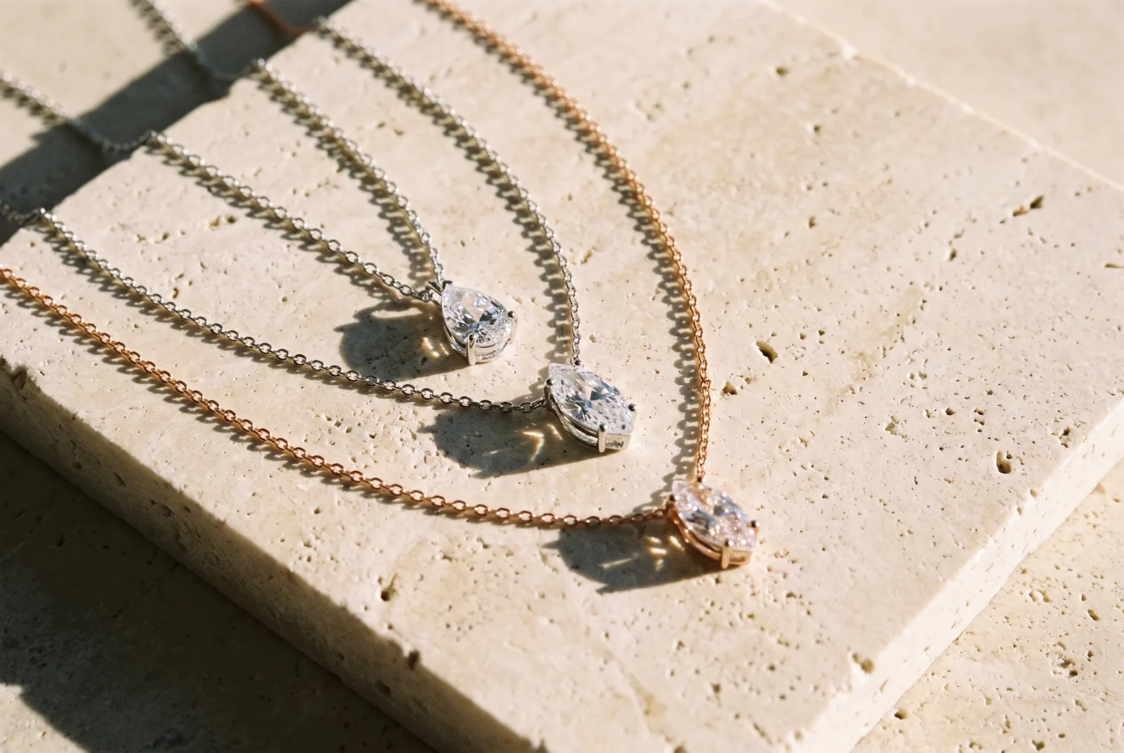 Three pendant necklaces on a stone slab